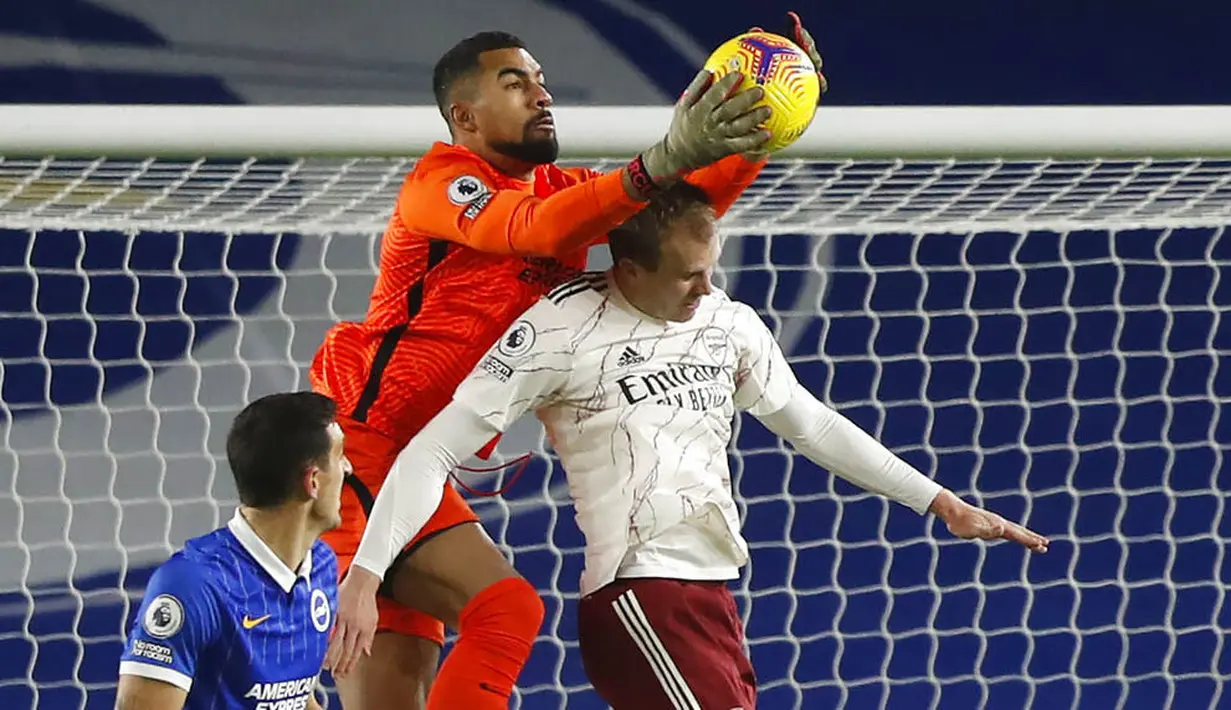 Pemain Arsenal, Rob Holding, berebut bola dengan kiper Brighton & Hove Albion, Robert Sanchez, pada laga Liga Inggris di Stadion Amex, Selasa (30/12/2020). Arsenal menang dengan skor 1-0. (AP/Frank Augstein, Pool)