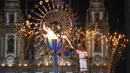 Atlet Brasil, Jorge Alberto Gomes, menyalakan obor Olimpiade dengan latar Gereja Candelaria pada pembukaan Olimpiade Rio 2016 di Rio de Janeiro (5/8/2016). (AFP/Mark Ralston)