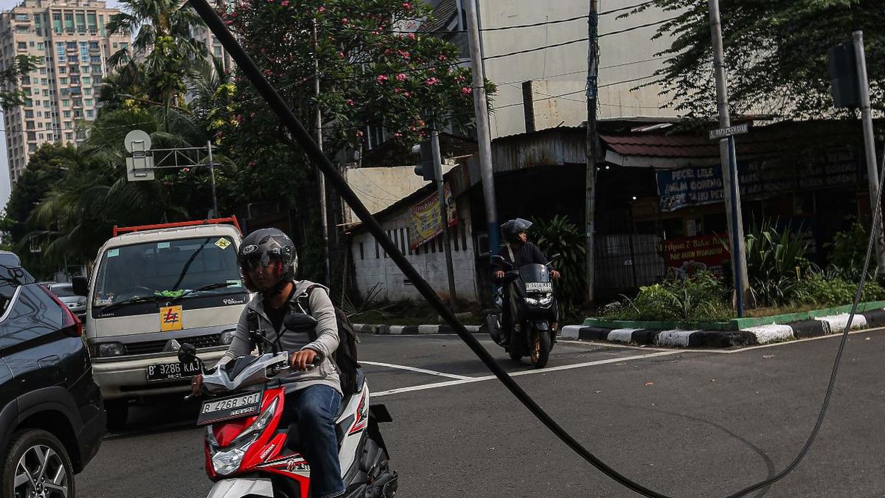 Sejumlah kendaraan melintas di dekat kabel menjuntai di Jalan Patal Senayan, Jakarta Selatan, Selasa (2/7/2024). Kabel tersebut menjuntai hingga nyaris menyentuh aspal setelah tersangkut pada sebuah truk bermuatan melebihi tinggi maksimum.&nbsp;Liputan6.c