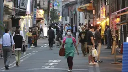 Orang-orang yang memakai masker berjalan di sepanjang jalan selama keadaan darurat di Tokyo, pada Senin (12/7/2021). Otoritas Jepang menempatkan Tokyo di bawah keadaan darurat Covid-19 keempat sebagai upaya menahan lonjakan kasus infeksi Corona dari Senin hingga 22 Agustus. (AP Photo/Koji Sasahara)