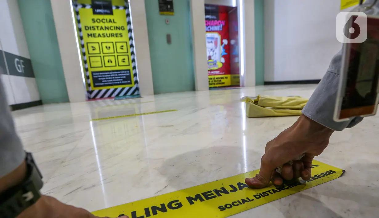 Pekerja memasang stiker saling menjaga jarak di depan lift Lippo Mall Puri, Jakarta, Rabu (3/6/2020). Lippo Malls Indonesia (LMI) menyiapkan prosedur dengan menerapkan protokol kesehatan menuju new normal di seluruh mal di 34 kota besar di Indonesia. (Liputan6.com/Fery Pradolo)