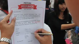 Seorang warga menulis petisi mendukung Gubernur Ahok di Bundaran HI, Jakarta, Minggu (1/3/2015). Aksi mereka sebagai bentuk dukungan kepada Ahok yangingin membongkar dana siluman di Pemprov DKI (Liputan6.com/Herman Zakharia)