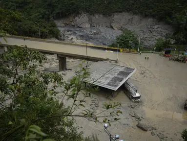 Sebuah truk tertutup lumpur di bawah jembatan yang ambruk saat longsoran maut yang juga melanda beberapa rumah di El Naranjal, Kolombia, Selasa, 18 Juli 2023. (AP Photo/Fernando Vergara)