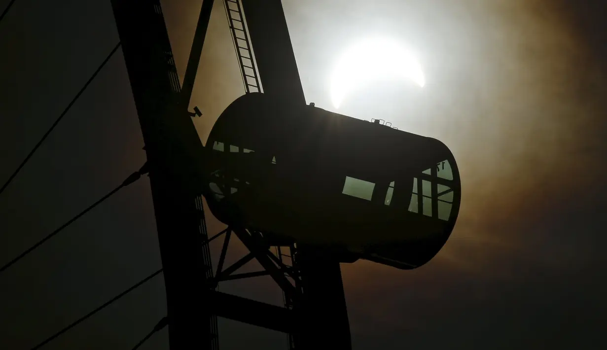 Siluet roda observatorium Singapore Flyer saat fenomena gerhana matahari parsial di Singapura, Rabu (9/3/2016). Gerhana matahari parsial di Singapura terakhir kali terjadi pada 10 Mei 2013 lalu. (REUTERS / Edgar Su)