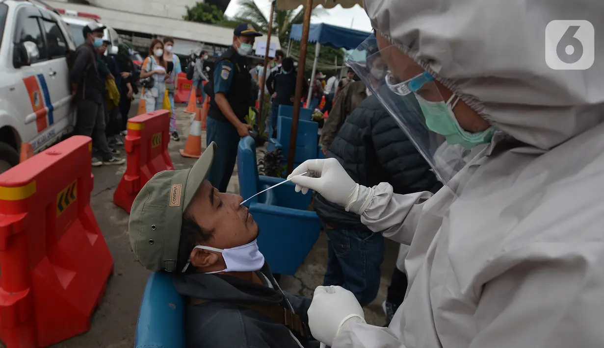 Petugas medis mengambil sampel lendir seorang pria untuk tes usap atau Swab Antigen di Pelabuhan Kali Adem, Jakarta, Kamis (31/12/2020). Pemeriksaan swab antigen wisatawan yang akan libur Tahun Baru di Kepulauan Seribu dilakukan untuk mencegah penyebaran COVID-19. (merdeka.com/Imam Buhori)