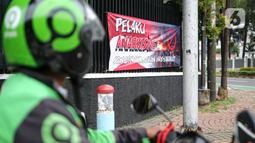 Pengendara motor melintas di dekat spanduk imbauan tolak anarkisme di Jakarta, Minggu (11/10/2020). Spanduk imbauan untuk tidak melakukan aksi anarkisme merebak di sejumlah kawasan di Jakarta pascaaksi unjuk rasa massa yang menolak pengesahan Omnibus Law UU Cipta Kerja. (Liputan6.com/Faizal Fanani)