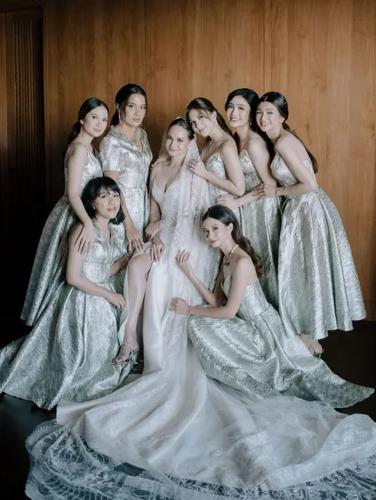 <p>Berbeda dari akad, para bridesmaid pernikahan Enzy tampil kompak mengenakan silk dress nuansa platinum yang mewah. [Foto: IG/enzystoria].</p>