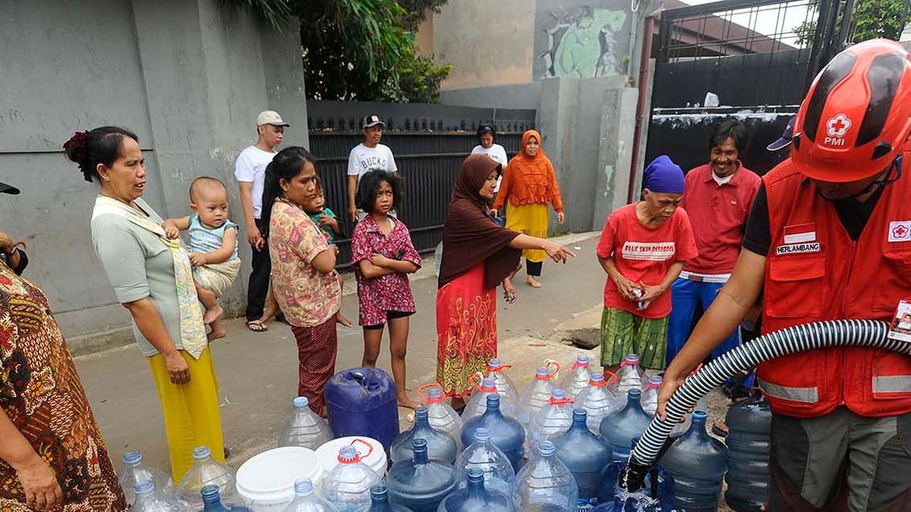 Petugas Palang Merah Indonesia (PMI) mengisi galon milik warga saat mendistribusikan bantuan air bersih di RW 10, Cipayung, Kota Depok, Kamis (14/9/2023).<br>