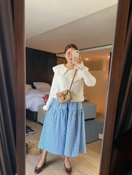 Tampil kasual dan manis dengan sweater warna broken white bersama blue gigham pattern skirt. Lengkapi gaya vintagemu dengan heels dan sling bag. (Instagram.com/lucedaleco).
