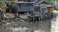 Anak-anak berenang di bawah jamban yang berada di bantaran Kali Ciliwung, Jakarta, Senin (19/11). Tak adanya akses sanitasi yang layak menyebabkan anak-anak menderita stunting. (Merdeka.com/Iqbal Nugroho)