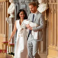 Pangeran Harry dan Meghan Markle berjalan membawa bayi laki-lakinya yang baru lahir di St George's Hall di Windsor Castle di Windsor, London (8/5/2019). Pangeran Harry menyatakan bahwa dia dan Meghan Markle masih memikirkan nama anak mereka. (AFP Photo/Dominic Lipinski)
