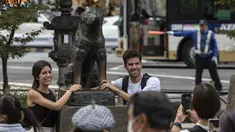 Pasangan berpose untuk berfoto di samping patung "Hachiko" di depan stasiun Shibuya di pusat kota Tokyo menjelang peringatan 100 tahun kelahiran anjing legendaris tersebut bulan ini pada 6 November 2023. (Richard A. Brooks / AFP)