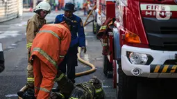 Petugas pemadam kebakaran membantu rekannya setelah melakukan pendingan di Kejaksaan Agung RI yang terbakar, Minggu (23/8/2020). Kebakaran di gedung Kejaksaan Agung pada Sabtu (22/8) malam akhirnya padam dan kini bangunan tersebut menyisakan bagian hitam legam. (Liputan6.com/Faizal Fanani)