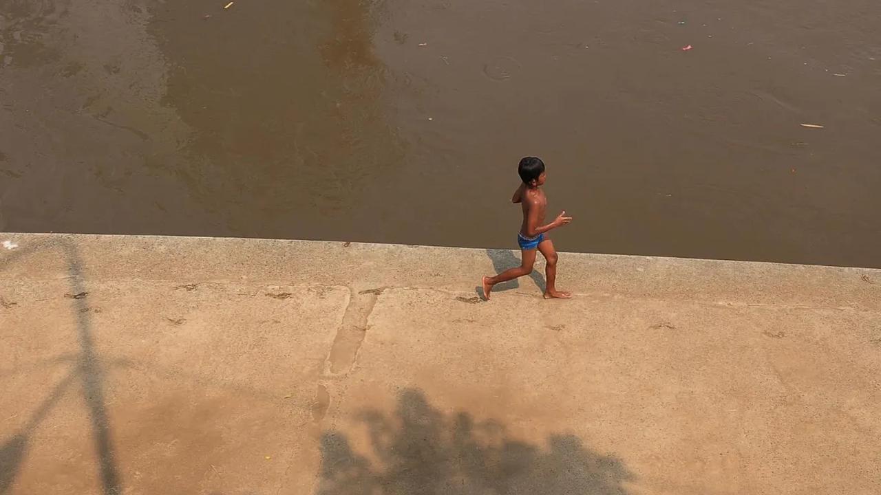 Seorang anak saat sedang asyik bermain di pinggiran kali Ciliwung di kawasan Cawang, Jakarta, Kamis (16/11/2023). Awal musim hujan di Indonesia diperkirakan mulai pada Oktober hingga Desember 2023.