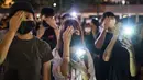 Mahasiswa menutup mata kanan mereka sambil menyalakan ponselnya selama rapat umum di Hong Kong (22/8/2019). para mahasiswa masih ingin memimpin barisan demonstran pro-demokrasi yang hampir setiap hari berada di jalanan untuk memberikan tekanan pada pemerintah. (AFP Photo/Anthony Wallace)