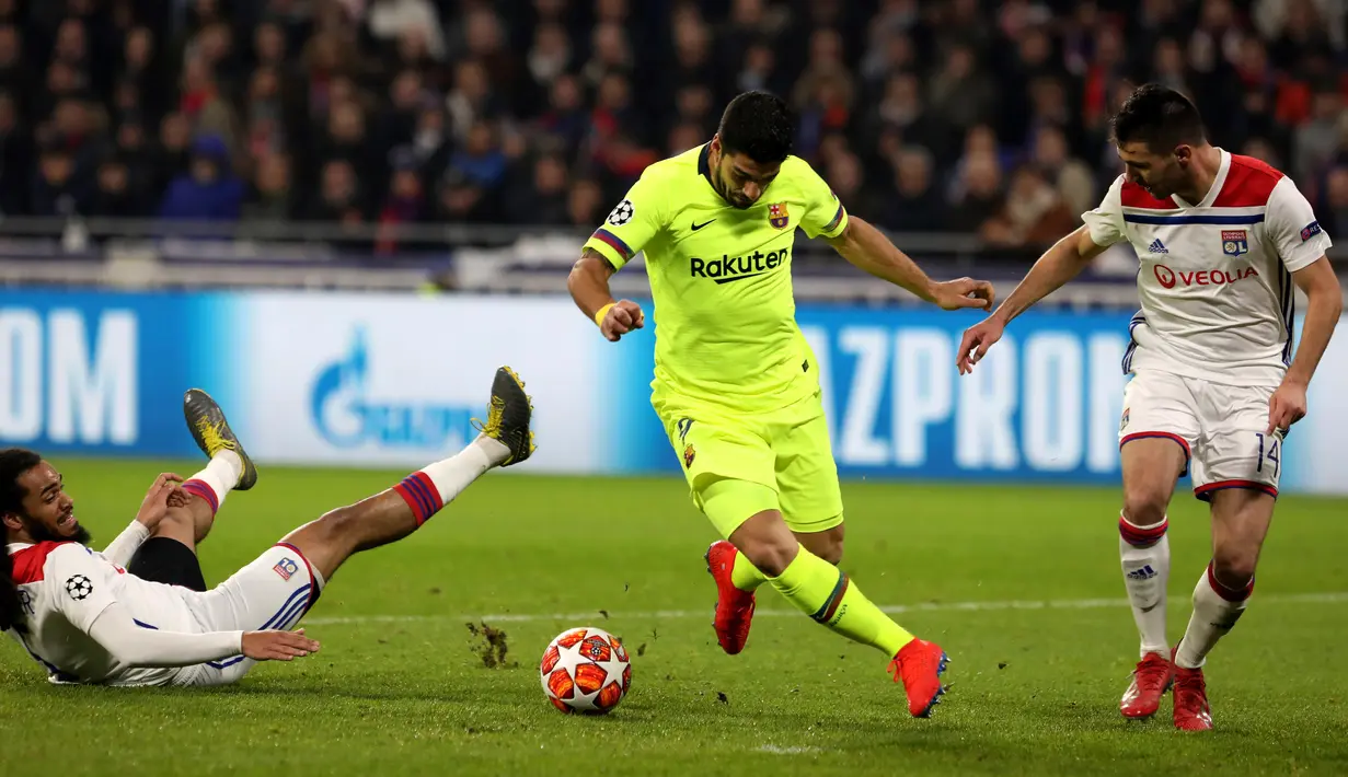 Penyerang Barcelona Luis Suarez (tengah) menggiring bola melewati bek Lyon Jason Denayer dan Leo Dubois pada leg pertama babak 16 besar Liga Champions di Decines, Lyon, Prancis, Selasa (19/2). Laga berakhir 0-0. (AP Photo/Laurent Cipriani)