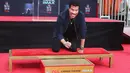 Lionel Richie membubuhkan tanda tangan sebelum mengabadikan cetak tangan dan kakinya di TCL Chinese Theatre, Hollywood, Rabu (7/3). Richie menerima berbagai penghargaan internasional dan penghargaan dari sejumlah negara. (Tommaso Boddi/Getty Images/AFP)