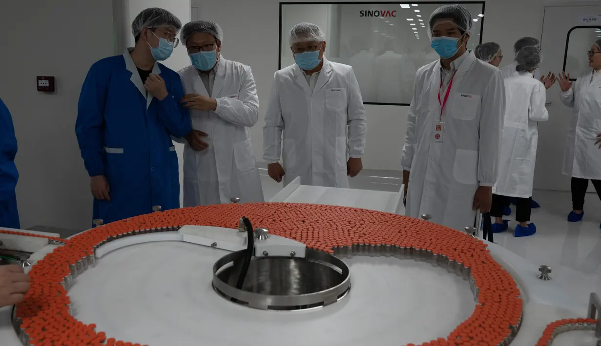 Pengunjung dan pekerja melihat botol Vaksin SARS CoV-2 untuk COVID-19 di pabrik vaksin SinoVac di Beijing, Kamis (24/9/2020). Perusahaan farmasi China, Sinovac mengatakan vaksin virus corona yang dikembangkannya akan siap didistribusikan ke seluruh dunia pada awal 2021. (AP Photo/Ng Han Guan)