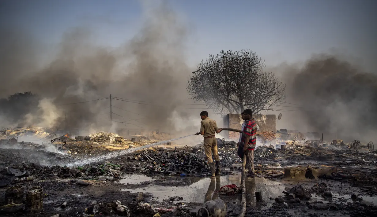 Petugas pemadam kebakaran mencoba memadamkan api di daerah kumuh di Noida, pinggiran kota New Delhi, India, Minggu (11/4/2021). Dua anak tewas dan lebih dari 150 gubuk kumuh yang sebagian besar dihuni oleh para pemulung dalam kebakaran pada Minggu sore. (AP Photo/Altaf Qadri)
