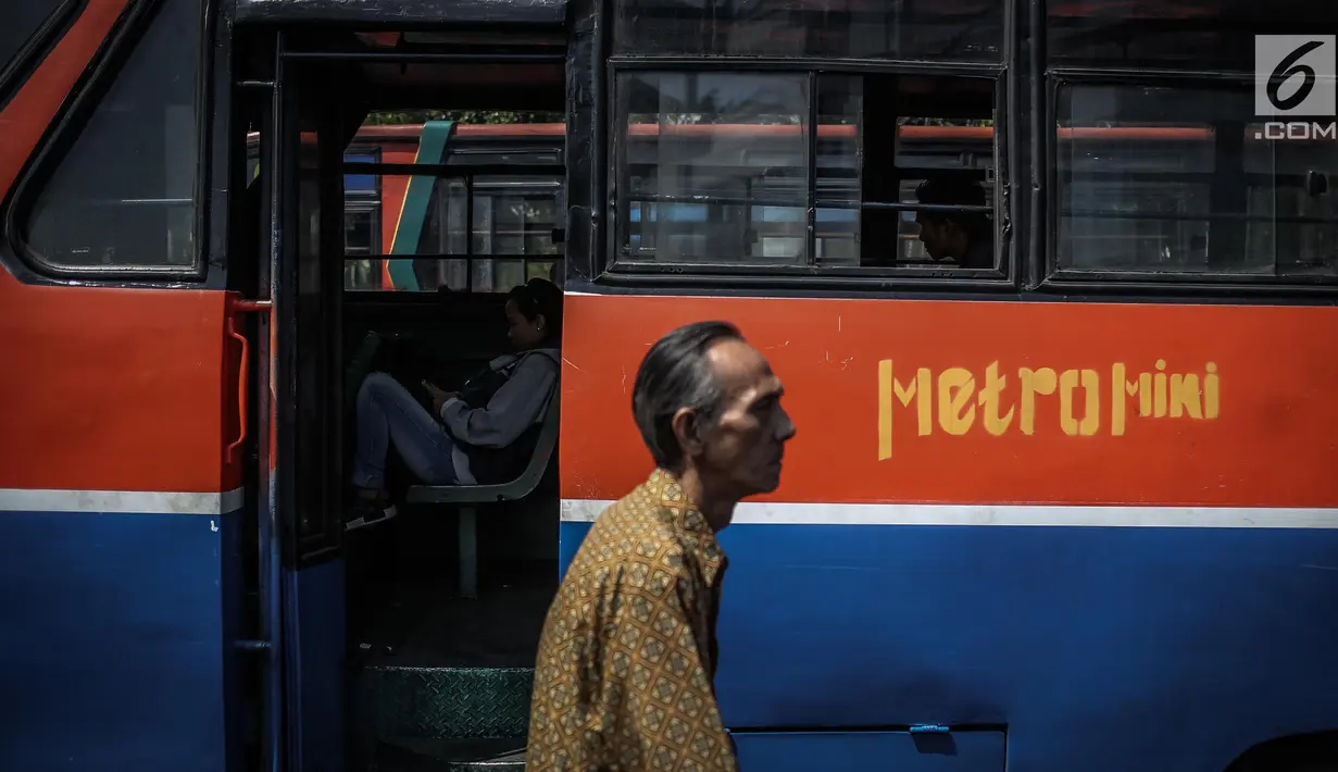 Seorang pria melintas diantara Metromini di Terminal Blok M, Jakarta, Rabu (26/7). Dinas Perhubungan (Dishub) DKI Jakarta akan merevitalisasi 700 unit metromini menjadi Minitrans. (Liputan6.com/Faizal Fanani)