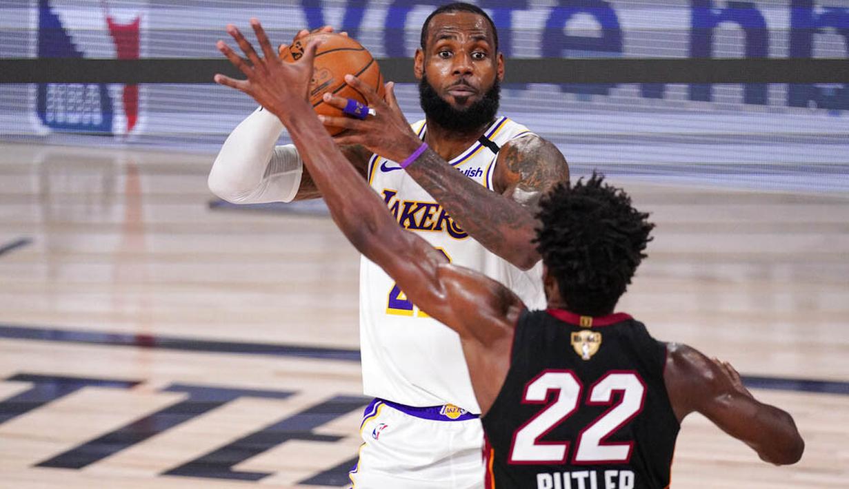 Pebasket Los Angeles Lakers, LeBron James, berusaha melewati pebasket Miami Heat, Jimmy Butler, pada laga Gim ketiga Final NBA, Senin (5/10/2020). Miami Heat menang dengan skor 115-104. (AP Photo/Mark J. Terrill)