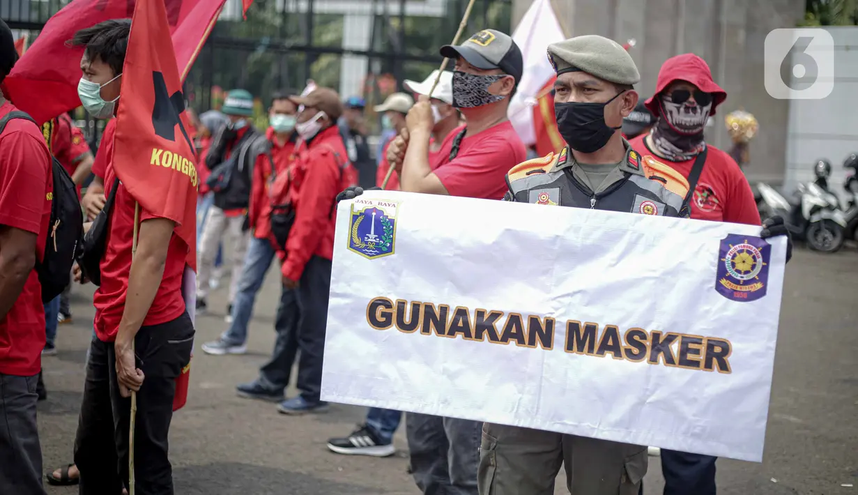 Petugas Satpol PP memegang poster imbauan protokol kesehatan COVID-19 saat unjuk rasa buruh di depan Gedung DPR, Jakarta, Selasa (17/11/2020). Pemerintah terus mengingatkan pentingnya 3M yaitu memakai masker, menjaga jarak, dan mencuci sebagai upaya pencegahan Covid-19. (Liputan6.com/Faizal Fanani)