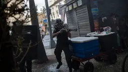Polisi menggunakan senjata menghalau para pengunjuk rasa saat bentrokan memprotes rencana pembatasan belanja publik di Rio de Janeiro, Brasil, (9/2). (AP Photo/Felipe Dana)