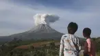 Dua orang Anak menyaksikan Gunung Sinabung memuntahkan material vulkanik saat meletus di Karo, Sumatera Utara, Kamis (11/3/2021). Gunung berapi tersebut mengeluarkan longsoran awan gas membakar yang mengalir menuruni lerengnya saat terjadi letusan pada hari Kamis. (AP Photo/Binsar Bakkara)