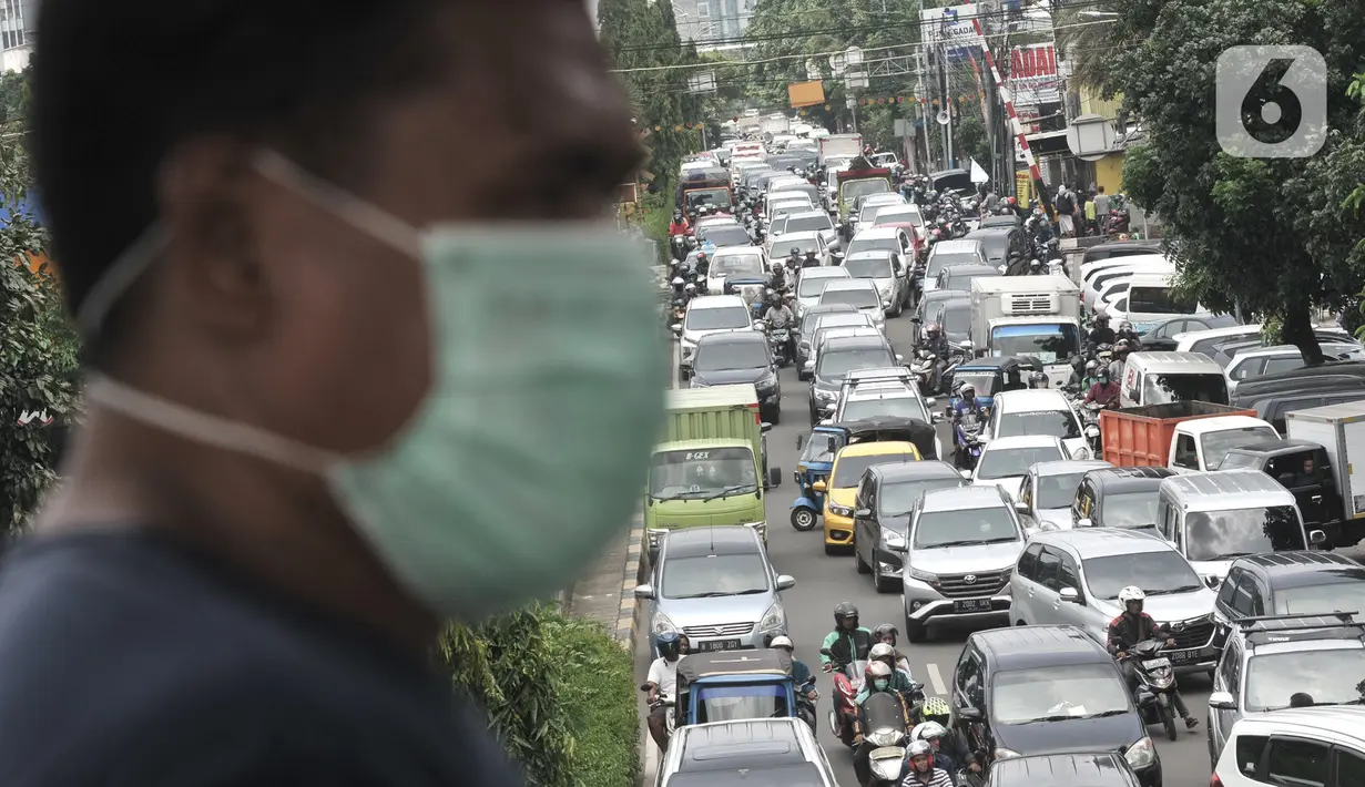 Warga melintasi JPO saat kemacetan terjadi di depan Pasar Pramuka, Jakarta, Senin (16/3/2020). Pasar Pramuka diserbu pembeli yang mencari masker guna mengantisipasi virus Corona, membuat sebagian badan jalan dimanfaatkan sebagai parkiran sehingga menyebabkan kemacetan. (merdeka.com/Iqbal Nugroho)