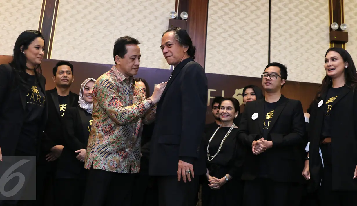 Ketua Badan Ekonomi Kreatif, Triawan Munaf menyematkan pin ke Wakil Ketua Umum Parfi 56 Ray Sahetapy pada acara pengukuhan dan pelantikan pengurus besar PARFI 56 (Persatuan Artis Film Indonesia) di Jakarta, Senin (24/10). (Liputan6.com/Herman Zakharia)