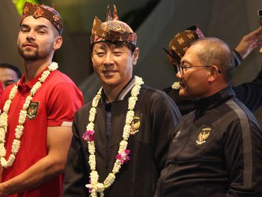 Pelatih Shin Tae-yong (tengah), dan pemain Timnas Indonesia, Sandy Walsh (kiri), memakai blangkon khas Jawa Timur saat menyapa masyarakat Surabaya dan sekitarnya dalam acara gala dinner dan meet &amp; greet yang berlangsung di Balai Kota Surabaya, Minggu (11/6/2023). (Bola.com/Wahyu Pratama)