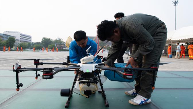 Seorang relawan untuk Bangkok Metropolitan Administration (BMA) mengisi ulang drone penghasil hujan yang menaburkan awan guna menurunkan hujan buatan selama demontrasi di ibu kota Thailand, Kamis (31/1). (Jewel SAMAD/AFP)