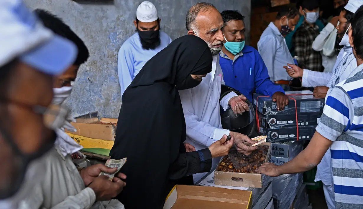Orang-orang membeli kurma di sepanjang jalan untuk bulan suci Ramadhan di Delhi, India pada Selasa (13/4/2021). Kurma sangat identik dengan bulan Ramadhan, karena buah yang satu ini kerap dijadikan pengisi menu sahur dan berbuka puasa. (Sajjad HUSSAIN / AFP)