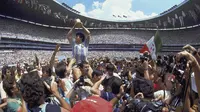 Penyerang Argentina, Diego Maradona, mengangkat trofi Piala Dunia saat usai mengalahkan Jerman Barat pada laga final Piala Dunia 1986 di Meksiko, (29/6/1986). (Photo by - / AFP)