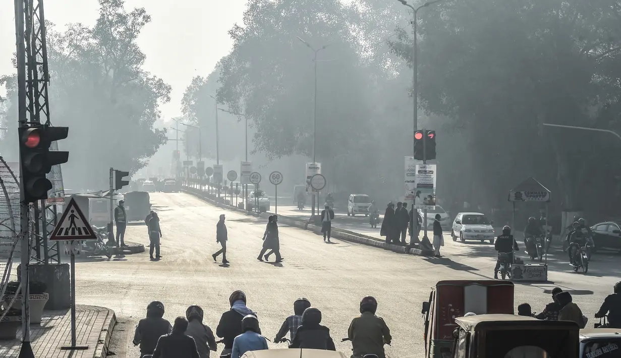 Orang-orang menyeberang jalan di tengah kondisi kabut asap di Lahore, Pakistan (23/11/2021). Kondisi kabut asap yang memburuk membuat Lembaga pendidikan, kantor swasta tutup selama tiga hari seminggu di Lahore. (AFP/Arif Ali)