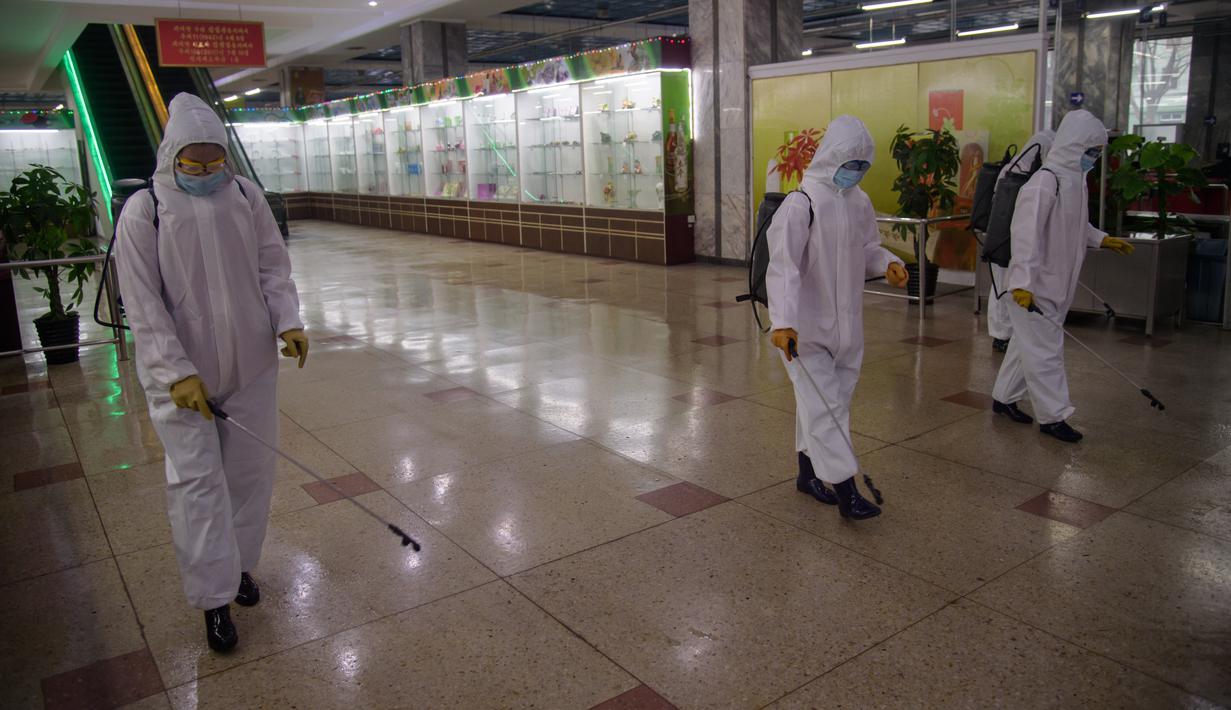 Petugas berpakaian APD melakukan penyemprotan cairan desinfektan di dalam Pyongyang Department Store No. 1, di Pyongyang, Korea Utara (28/12/2020). Protokol kesehatan diterapkan dengan melakukan desinfektan, pemeriksaan suhu tubuh hingga memakai masker. (AFP/Kim Won Jin)