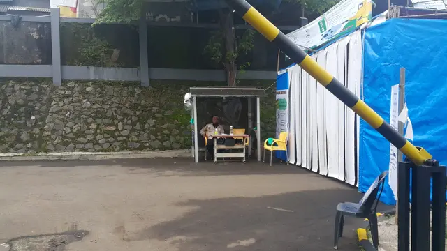Petugas keamanan juga bertugas sebagai pengukur suhu di depan pintu masuk salah satu perumahan di Tangerang Selatan