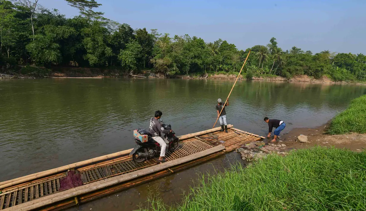 Warga bersama sepeda motornya menyeberangi Sungai Cisadane menggunakan rakit bambu di kawasan Ciseeng, Kabupaten Bogor, Jawa Barat, Kamis (11/6/2026). (merdeka.com/Arie Basuki)