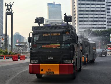 Kendaraan water canon Brimob Polda Metro Jaya menyemprotkan air di kawasan Bundaran HI, Jakarta, Rabu (23/8/2023). Pemerintah Provinsi (Pemprov) DKI Jakarta dan Polda Metro Jaya melakukan penyemprotan air di sepanjang Jalan Medan Merdeka Barat hingga Patung Pemuda Membangun Senayan sebagai upaya untuk mengurangi polusi udara dan mengatasi cuaca panas di Ibu Kota. (Liputan6.com/Angga Yuniar)