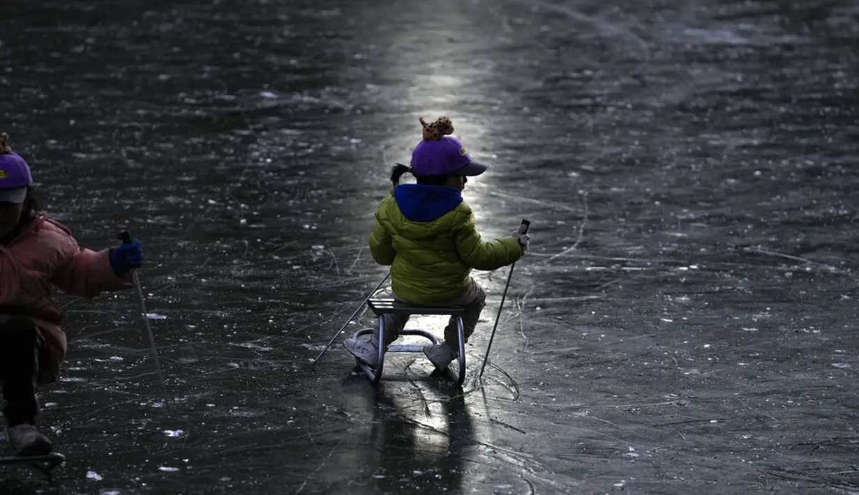 Anak-anak bermain ice skating di sungai yang membeku dekat pemukiman warga, Beijing, China, 3 Januari 2022. Libur Tahun Baru dimanfaatkan warga untuk bermain ice skating di sungai dan danau yang membeku. (AP Photo/Andy Wong)