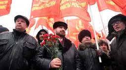 Sejumlah orang membawa bendera dan bunga saat menghadiri upacara memperingati 65 tahun kematian Joseph Stalin di Lapangan Merah, Moskow (5/3). (AFP/Kirill Kudryavtsev)