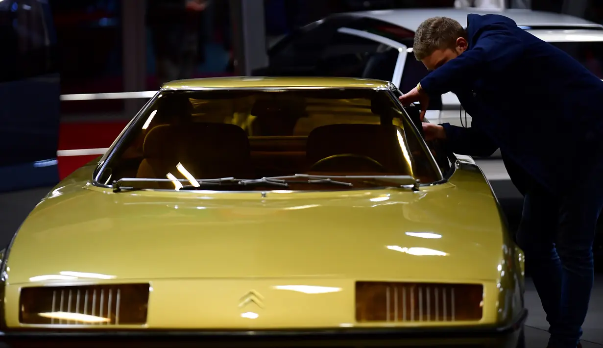 Seorang lelaki memandangi sebuah mobil tua yang ditampilkan selama pameran mobil klasik Retromobile di Porte de Versailles, di Paris (4/2/2020). Retromobile berlangsung dari 5 Februari hingga 9 Februari 2020. (AFP Photo/Martin Bureau)