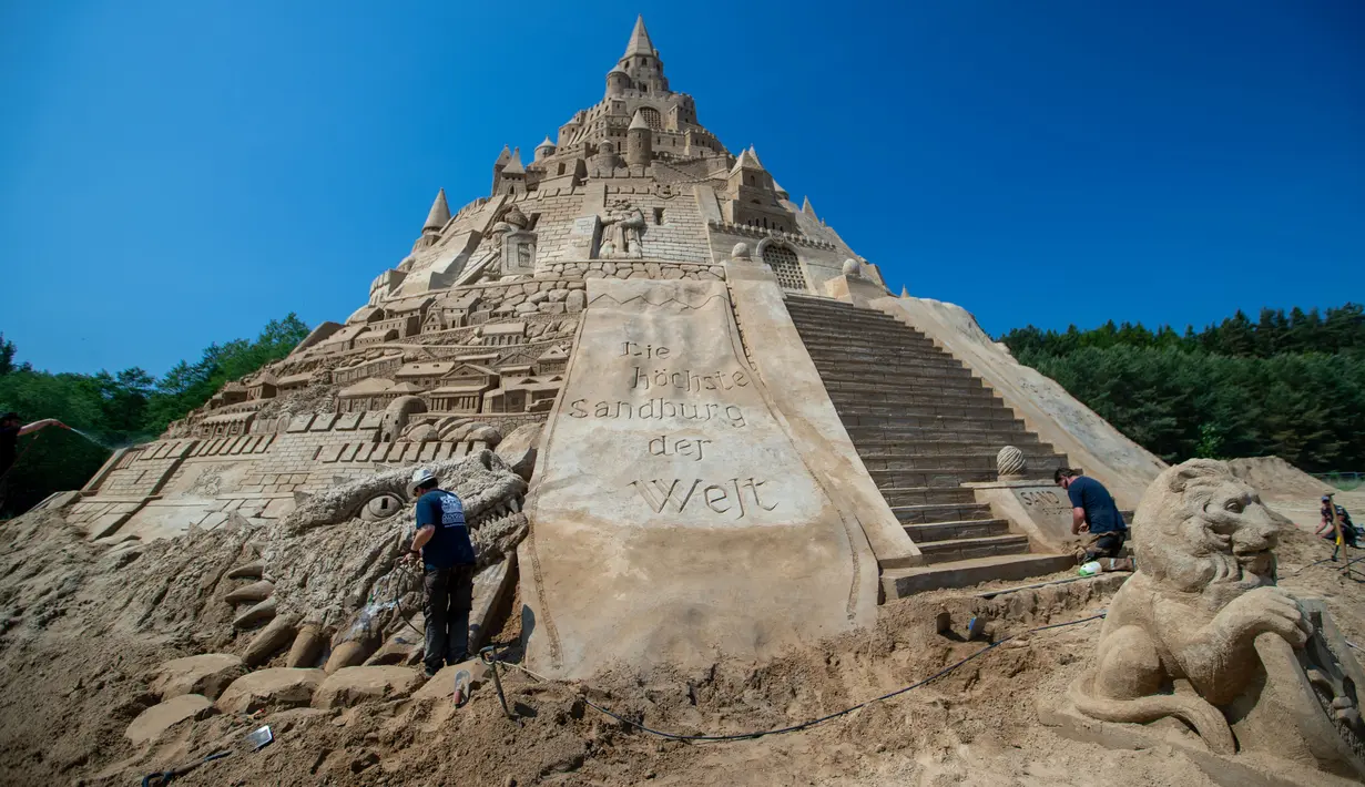 Pemahat beraktivitas di istana pasir tertinggi pada kompetisi tahunan "Sand Sculptures Festival" di Binz, Pulau Reugen di Laut Baltik, Jerman, 5 Juni 2019. Istana pasir itu berhasil memecahkan rekor sebagai istana pasir tertinggi di dunia dengan rincian ketinggian 17,66 meter. (Jens Büttner/dpa/AFP)