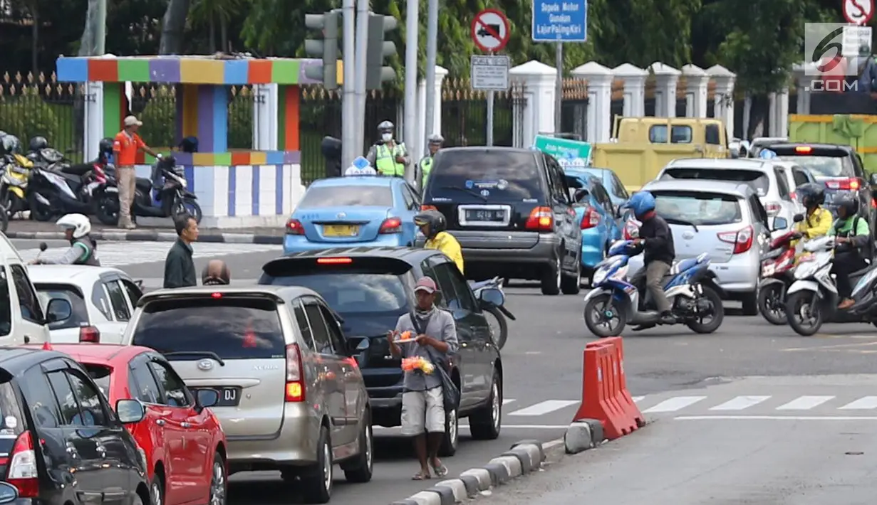 Pedagang asongan menjajakan barang dagangannya di persimpangan lampu merah di Jakarta, Jumat (22/2). Keahlian yang terbatas menyebabkan sebagian orang harus bekerja di tengah padatnya kendaraan Ibukota. (Liputan6.com/Immanuel Antonius)
