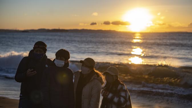 Orang-orang berkumpul di Pantai Selatan Chigasaki untuk menyaksikan matahari terbit pada Hari Tahun Baru di Prefektur Kanagawa, barat daya Tokyo (1/1/2021). (AFP/Philip Fong)