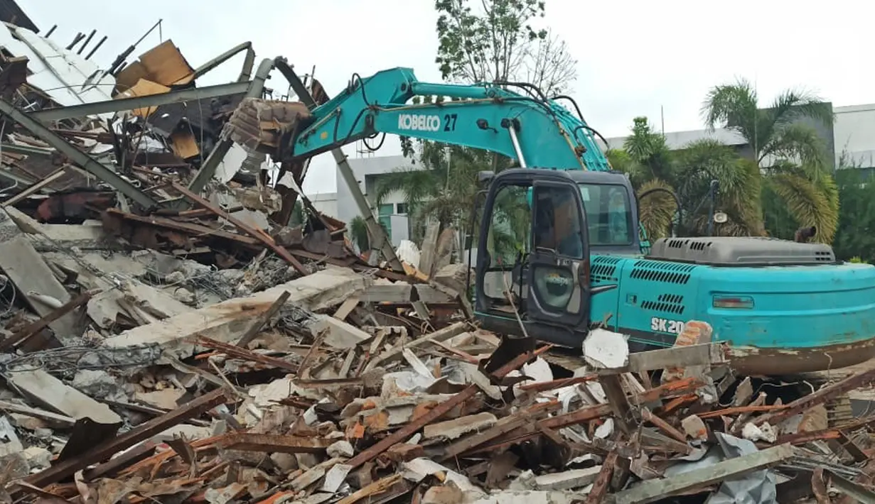 Sejumlah alat berat tengah melakukan evakuasi dan pembersihan puiang-puing Kantor Gubernur Sulawesi Barat Pasca Gempa Bumi dengan Magnitudo 6,2 mengguncang Majene pada Jumat 15 Januari 2021. (Liputan6.com/Abdul Rajab Umar)