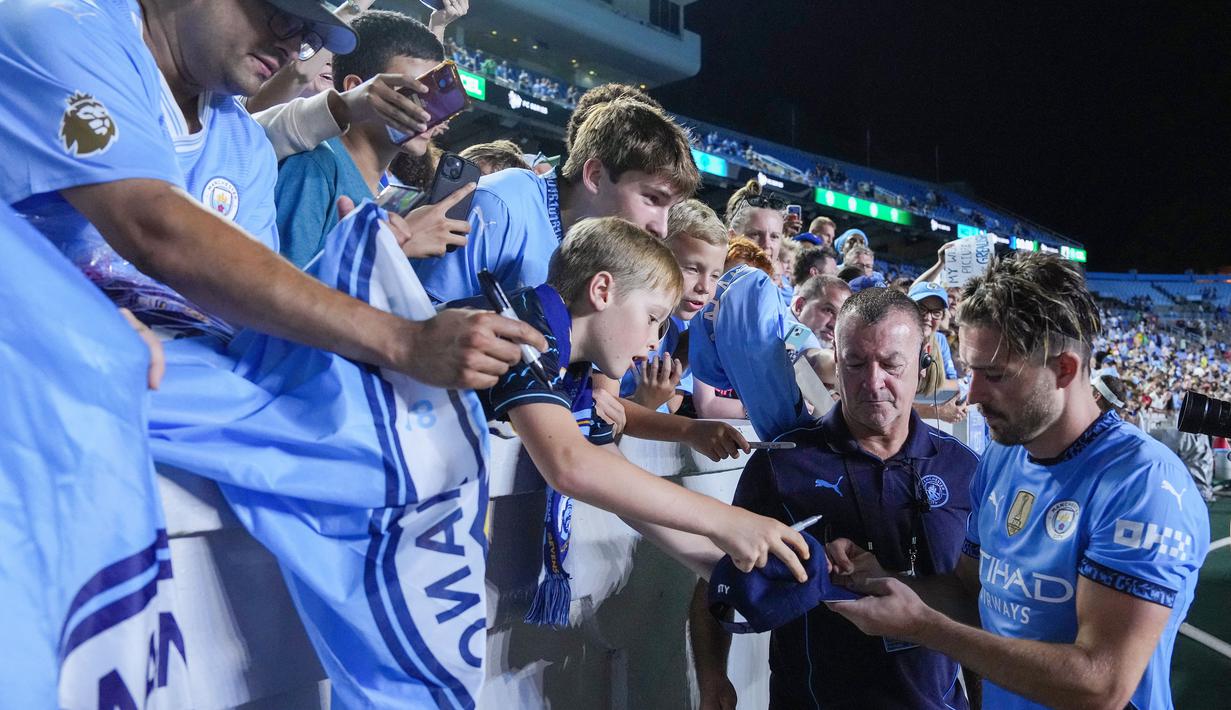 Pemain Manchester City, Jack Grealish, memberikan tanda tangan kepada fans setelah laga melawan Glasgow Celtic pada laga uji coba di Stadion Kenan Memorial, Rabu (24/7/2024). (AFP/Grant Halverson)