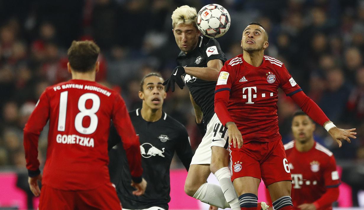 Gelandang Bayern Munich, Thiago, duel udara dengan pemain RB Leipzig, Kevin Kampl, pada laga Bundesliga di Allianz Arena, Kamis (20/12). Bayern Munich menang 1-0 atas RB Leipzig. (AP/Matthias Schrader)