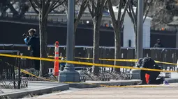 Petugas kepolisian mengambil gambar lokasi bunuh diri seorang pria di depan Gedung Putih, Washington, Amerika Serikat, Sabtu (3/3). Tidak ada korban jiwa selain pria tersebut. (AP Photo/Pablo Martinez Monsivais)