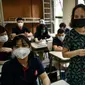 Seorang guru membagikan masker kepada siswa di dalam kelas di sekolah Marie Curie di Hanoi, Senin (4/5/2020). Vietnam membuka kembali aktivitas sekolah yang ditutup selama tiga bulan setelah dilaporkan tidak ada kasus virus corona COVID-19 baru hingga Sabtu, 2 Mei 2020. (Manan VATSYAYANA/AFP)